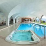 in primo piano una grande vasca idromassaggio e dietro una piscina termale al chiuso