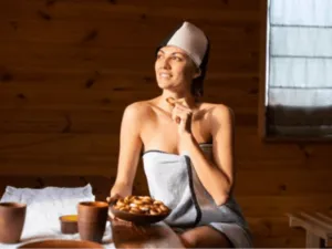 una donna in accappatoio e turbante alle terme con un piattino di frutta