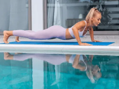 una donna fa esercizi di plank sul bordo della piscina termale