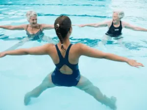 due signore anziane fanno acqua gim in una piscina termale con istruttrice