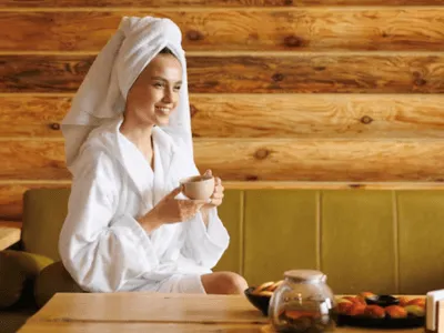 una donna in accappatoio e turbante beve una tisana alle terme