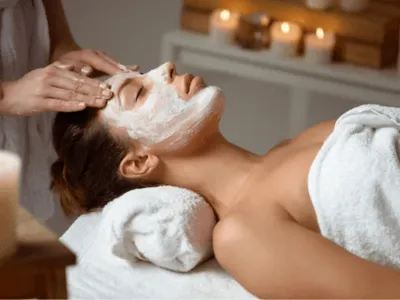 una donna effettua un trattamento sul viso sullo sfondo delle candela