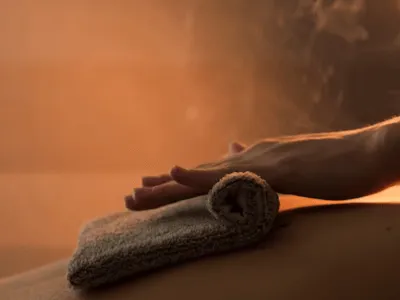 una sala massaggi in una sauna con asciugamani e delle mani con vapore intorno